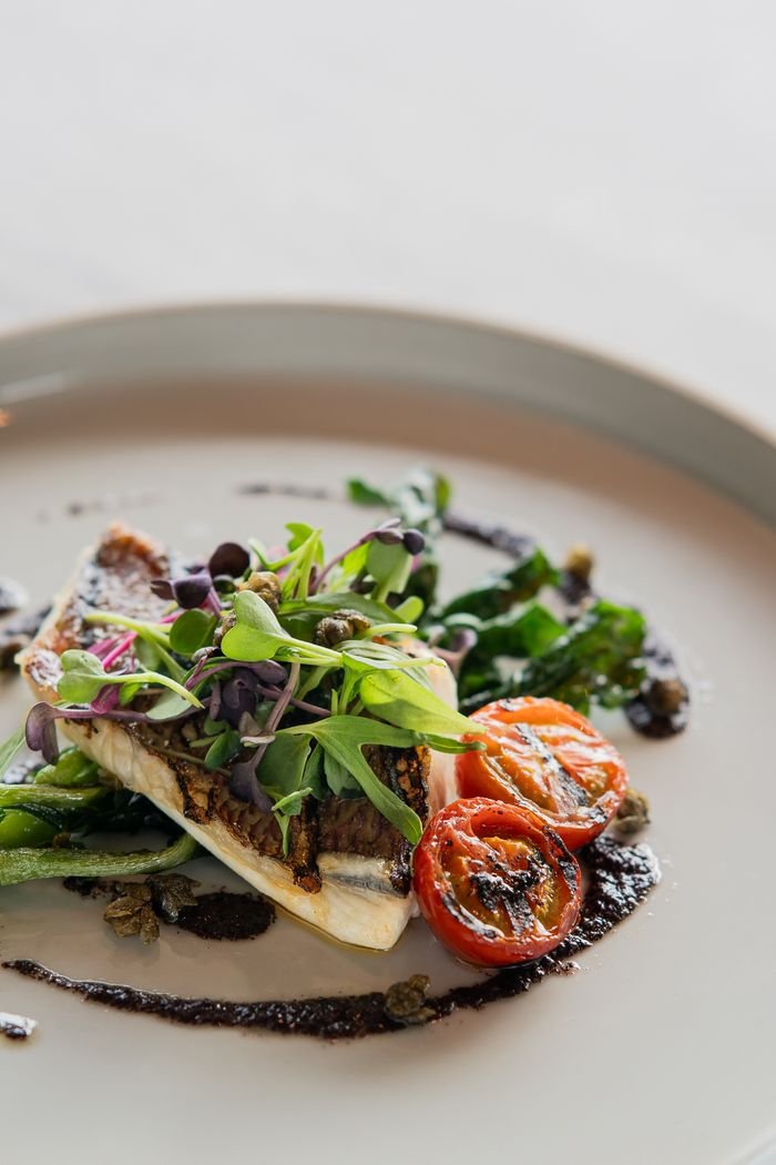 A beautifully plated gourmet dish with grilled vegetables and microgreens in a Tokyo restaurant.