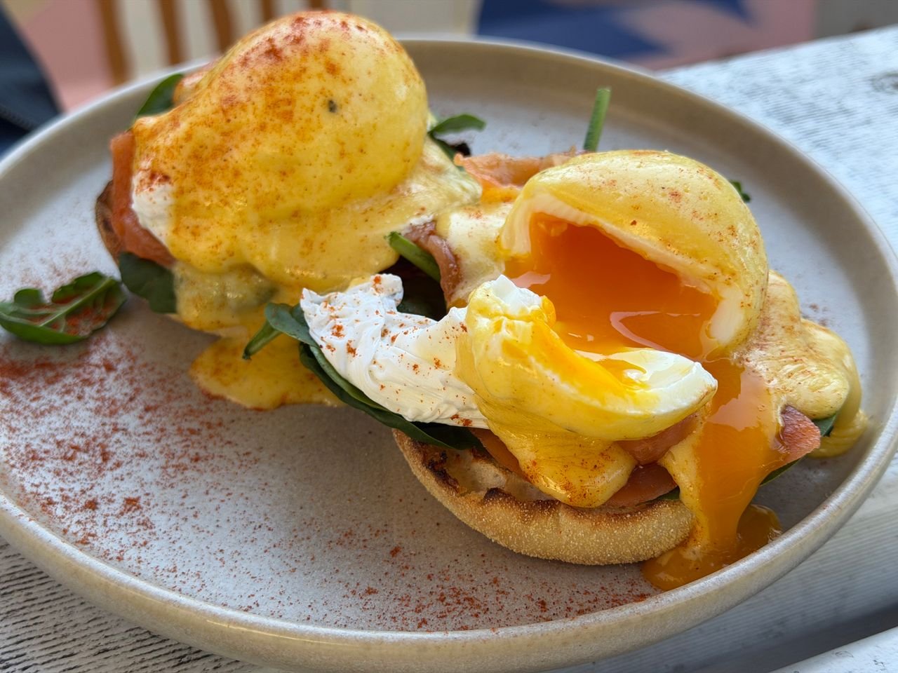 about-us Close-up of a delicious eggs benedict with runny yolk on a stylish plate.